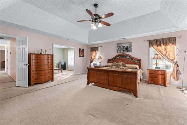 bedroom featuring baseboards, light colored carpet, a textured ceiling, and a tray ceiling