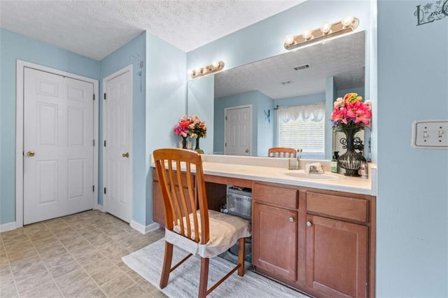 bathroom with visible vents, baseboards, a textured ceiling, and vanity