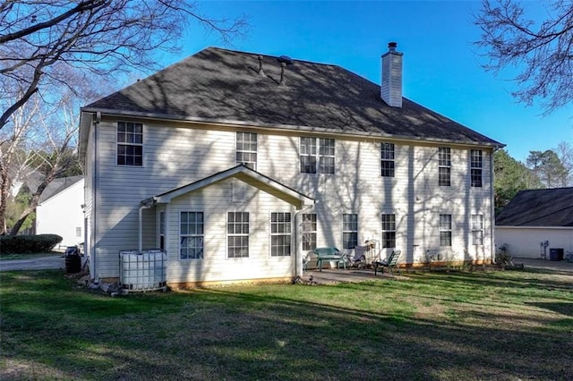 back of house with a patio, a yard, and a chimney