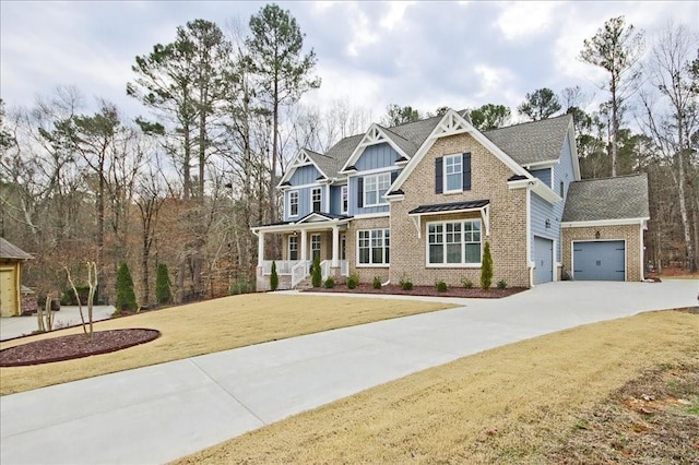 craftsman inspired home with a garage, concrete driveway, covered porch, a front lawn, and brick siding