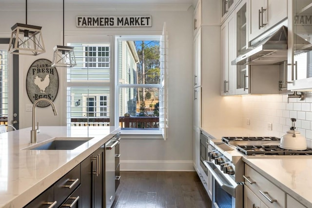 kitchen featuring stainless steel range, light stone countertops, pendant lighting, white cabinets, and sink