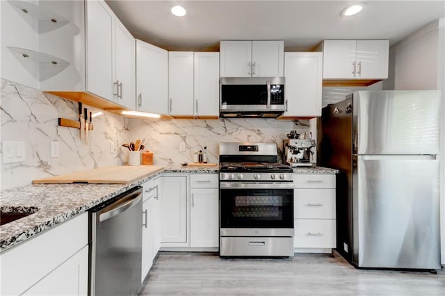 4417 Village Square Ln, Stone Mountain, GA 30083 - kitchen with stainless steel appliances, light stone countertops, white cabinets, decorative backsplash, and recessed lighting
