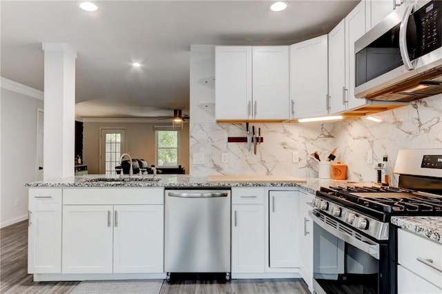 4417 Village Square Ln, Stone Mountain, GA 30083 - kitchen featuring appliances with stainless steel finishes, light stone countertops, crown molding, light wood-type flooring, and white cabinets