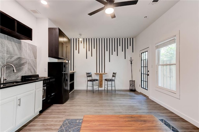 4417 Village Square Ln, Stone Mountain, GA 30083 - kitchen featuring black appliances, a ceiling fan, light wood-style flooring, white cabinets, and dark countertops