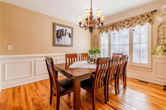 dining area featuring crown molding, light hardwood / wood-style flooring, and a notable chandelier