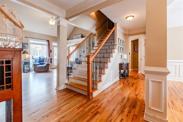 stairs featuring ornate columns, ornamental molding, and hardwood / wood-style flooring