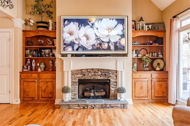 living room with light hardwood / wood-style floors, lofted ceiling, and a fireplace