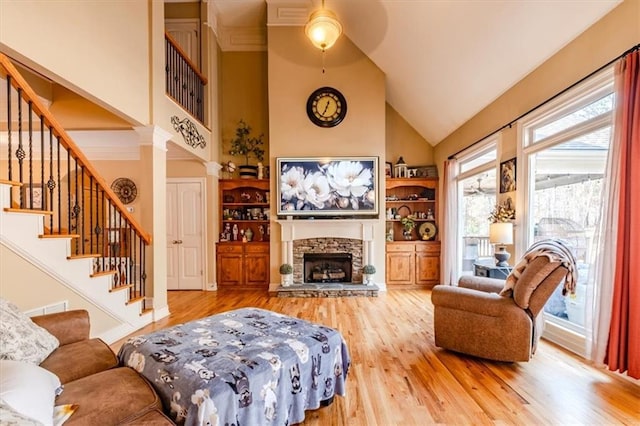 living room with decorative columns, ceiling fan, high vaulted ceiling, light hardwood / wood-style flooring, and a fireplace