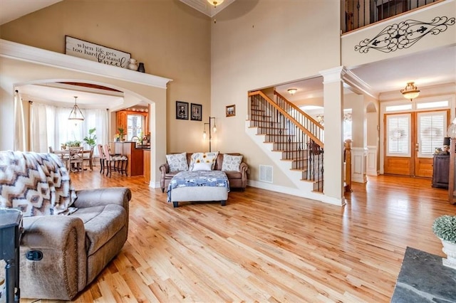 living room featuring decorative columns, a high ceiling, and light wood-type flooring