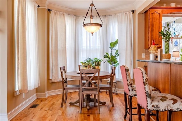 dining space with light hardwood / wood-style flooring, a healthy amount of sunlight, and crown molding