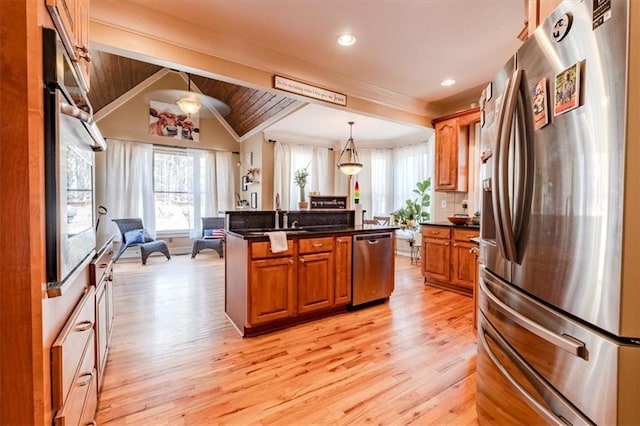 kitchen with pendant lighting, a kitchen island with sink, lofted ceiling with beams, light hardwood / wood-style flooring, and appliances with stainless steel finishes