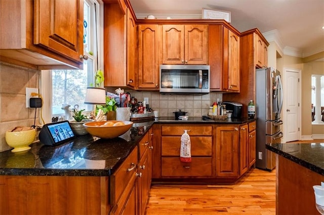 kitchen featuring stainless steel appliances, light hardwood / wood-style flooring, dark stone countertops, crown molding, and decorative backsplash