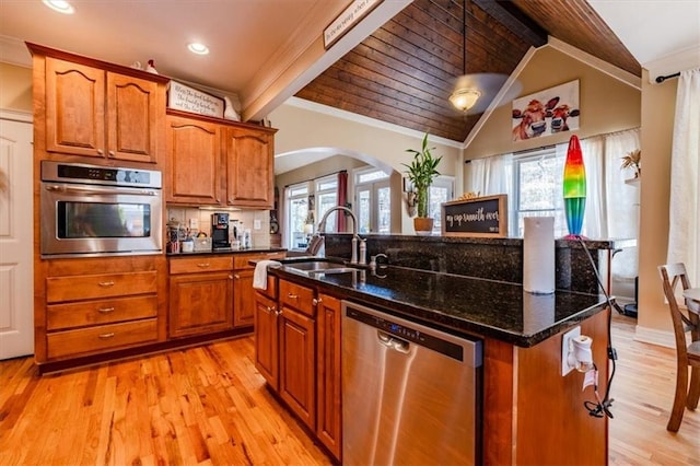 kitchen with appliances with stainless steel finishes, lofted ceiling with beams, a healthy amount of sunlight, and an island with sink