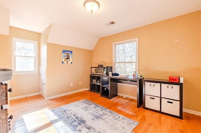 office space featuring light wood-type flooring, a wealth of natural light, and lofted ceiling