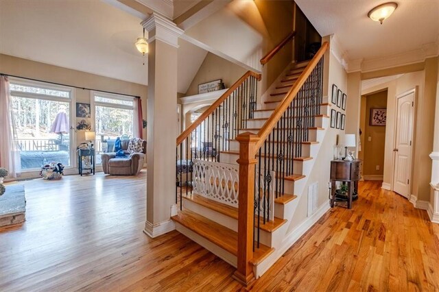 stairs featuring hardwood / wood-style flooring, high vaulted ceiling, and decorative columns