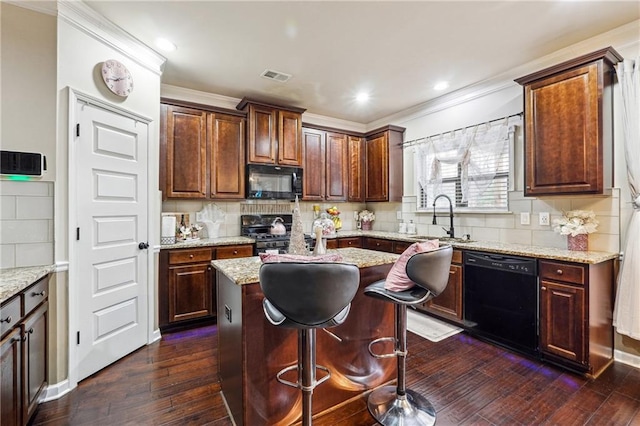 kitchen featuring light stone counters, sink, black appliances, and a center island