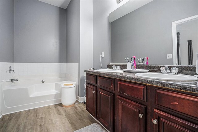 bathroom with a tub to relax in, vanity, and hardwood / wood-style flooring