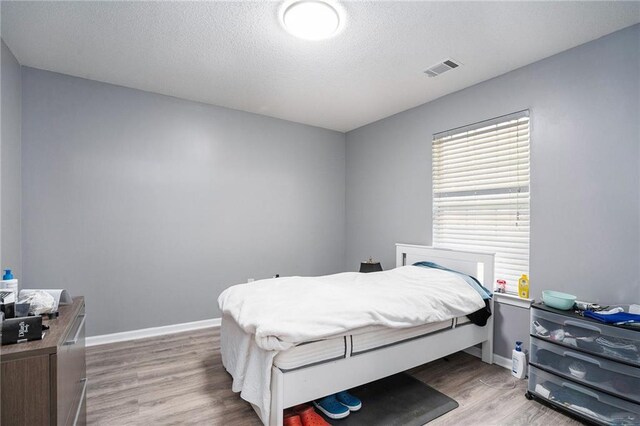 bedroom with hardwood / wood-style floors and a textured ceiling