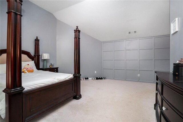 bedroom with light colored carpet and vaulted ceiling