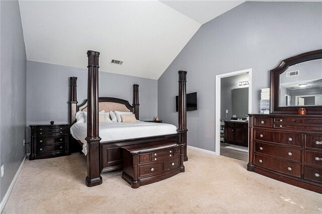 bedroom with light carpet, ensuite bath, and lofted ceiling