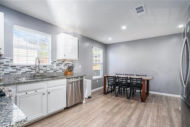 kitchen featuring white cabinets, stainless steel appliances, plenty of natural light, and sink