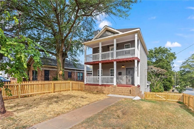 view of front facade featuring covered porch, a balcony, and a front lawn