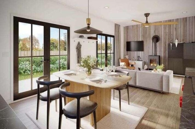 dining space with french doors, light hardwood / wood-style floors, a wood stove, and ceiling fan