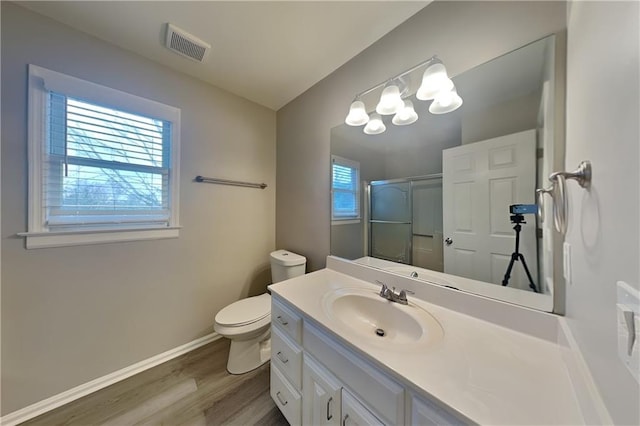 bathroom with hardwood / wood-style floors, toilet, an enclosed shower, and vanity