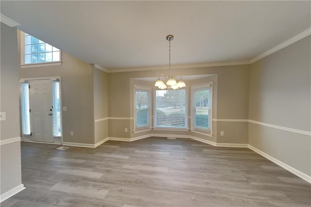 unfurnished dining area featuring a notable chandelier, hardwood / wood-style flooring, and crown molding