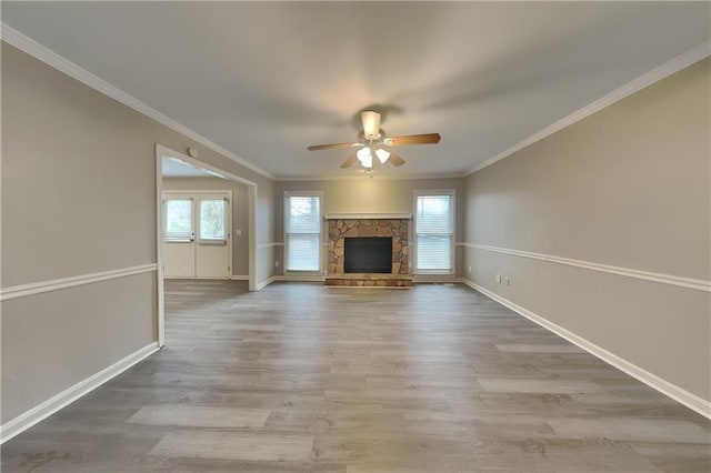 unfurnished living room with crown molding, hardwood / wood-style floors, ceiling fan, and a stone fireplace