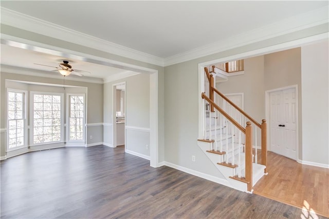spare room featuring crown molding, baseboards, stairs, a ceiling fan, and dark wood-type flooring