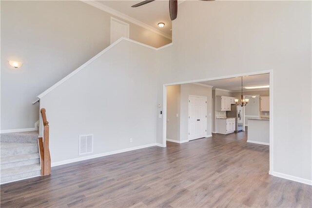 unfurnished living room featuring ceiling fan with notable chandelier, visible vents, stairway, and ornamental molding