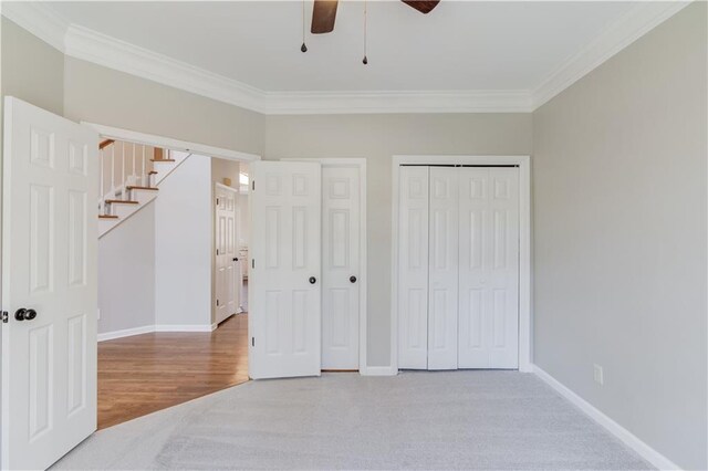 carpeted bedroom with baseboards, two closets, and ornamental molding
