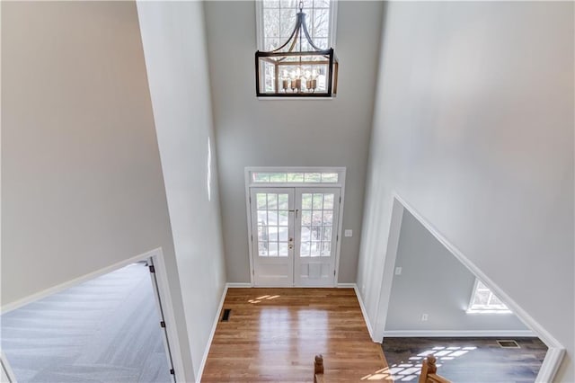 foyer entrance featuring visible vents, baseboards, wood finished floors, a high ceiling, and french doors
