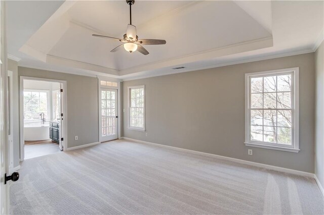 empty room featuring light colored carpet, a ceiling fan, baseboards, and a raised ceiling