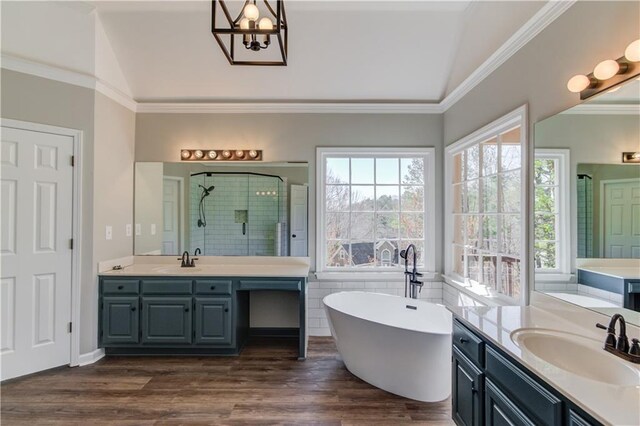 full bath with crown molding, a sink, a shower stall, and wood finished floors