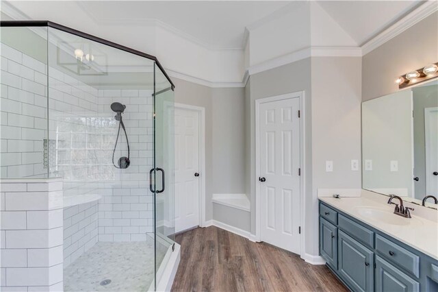 bathroom with vanity, ornamental molding, baseboards, a shower stall, and wood finished floors