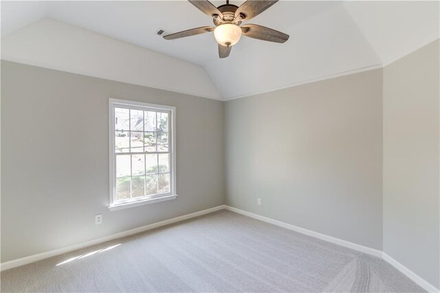 carpeted empty room with a ceiling fan, baseboards, and vaulted ceiling