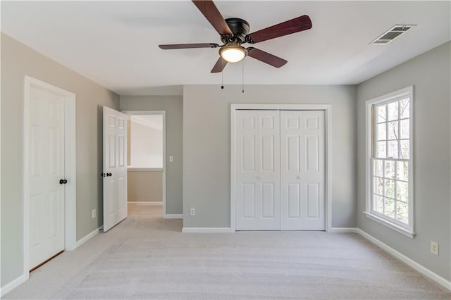 unfurnished bedroom featuring baseboards, visible vents, a ceiling fan, light carpet, and a closet