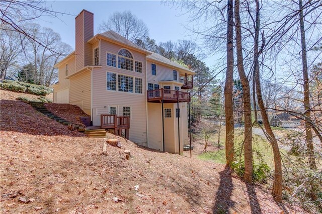 rear view of property with a chimney, a garage, and a deck