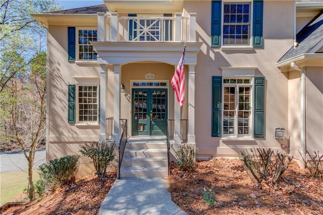 doorway to property with french doors, a balcony, and stucco siding