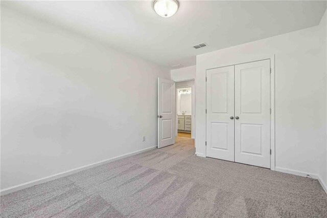 unfurnished bedroom with light carpet and a closet