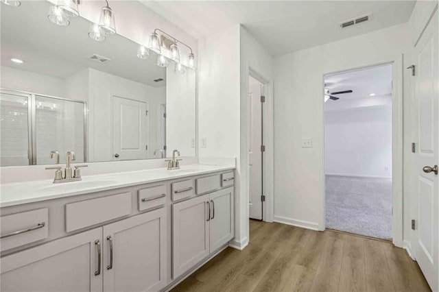 bathroom featuring ceiling fan, vanity, wood-type flooring, and a shower with shower door