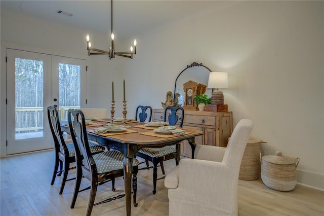 dining area with french doors, a chandelier, light wood-type flooring, and baseboards