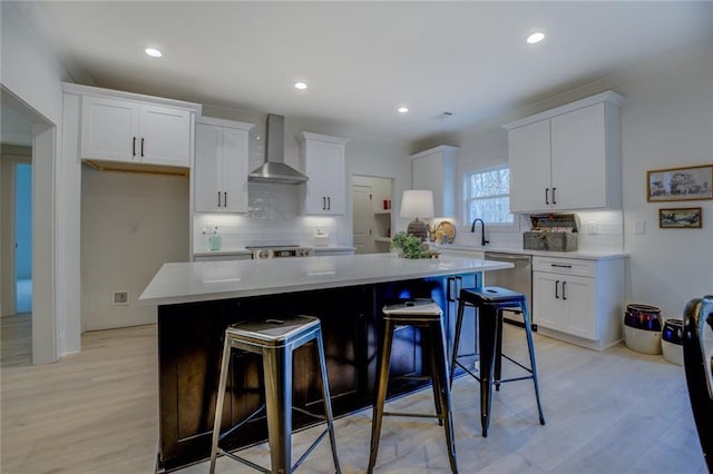 kitchen featuring wall chimney range hood, dishwasher, decorative backsplash, white cabinets, and recessed lighting