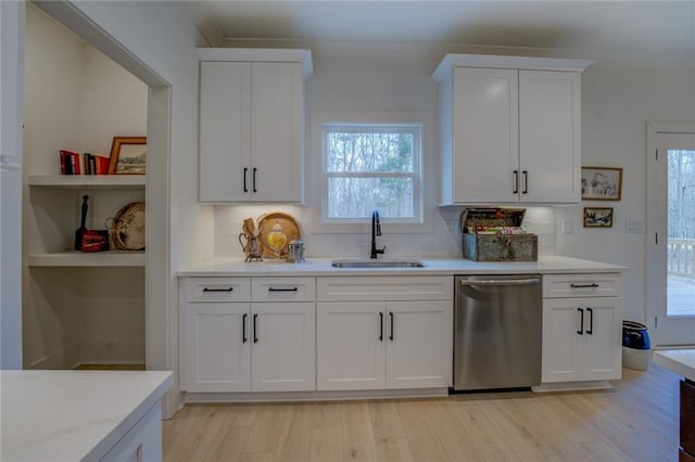 kitchen featuring dishwasher, a sink, light countertops, and tasteful backsplash