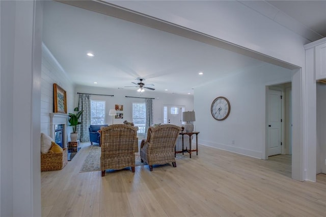 living room featuring light wood-style floors, ceiling fan, baseboards, a glass covered fireplace, and recessed lighting
