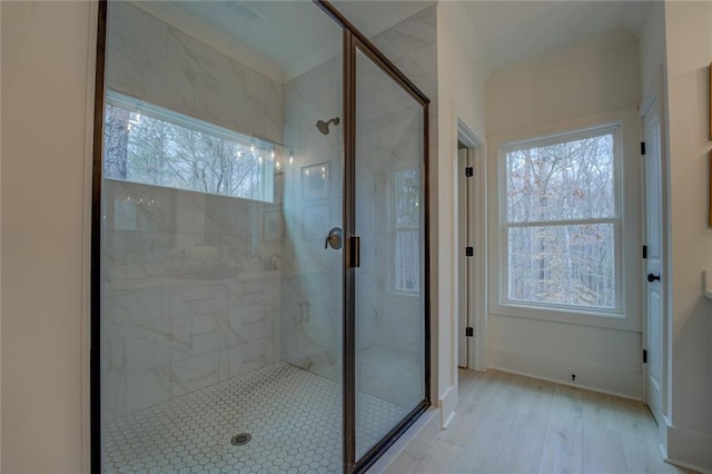 bathroom featuring a marble finish shower, wood finished floors, and baseboards