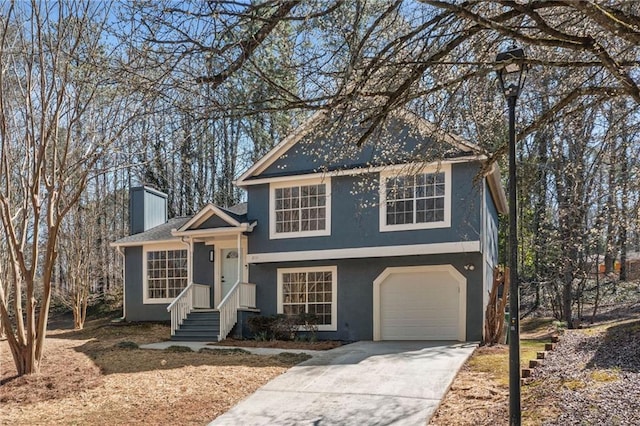 tri-level home featuring driveway, an attached garage, and stucco siding