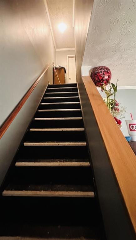 staircase with a textured ceiling and crown molding